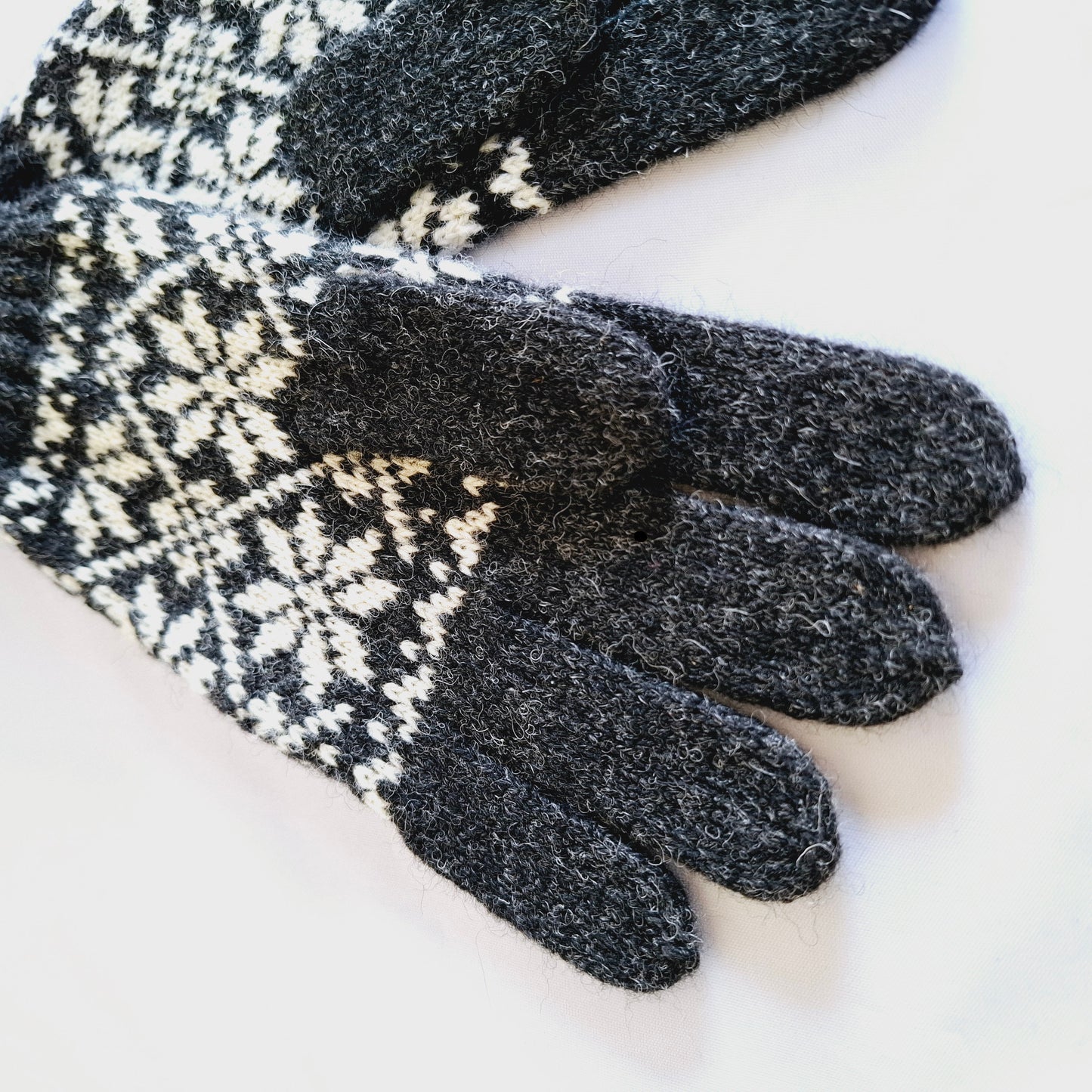 Gestrickte Wollhandschuhe in Hellgrau mit schwarzen Sternen.