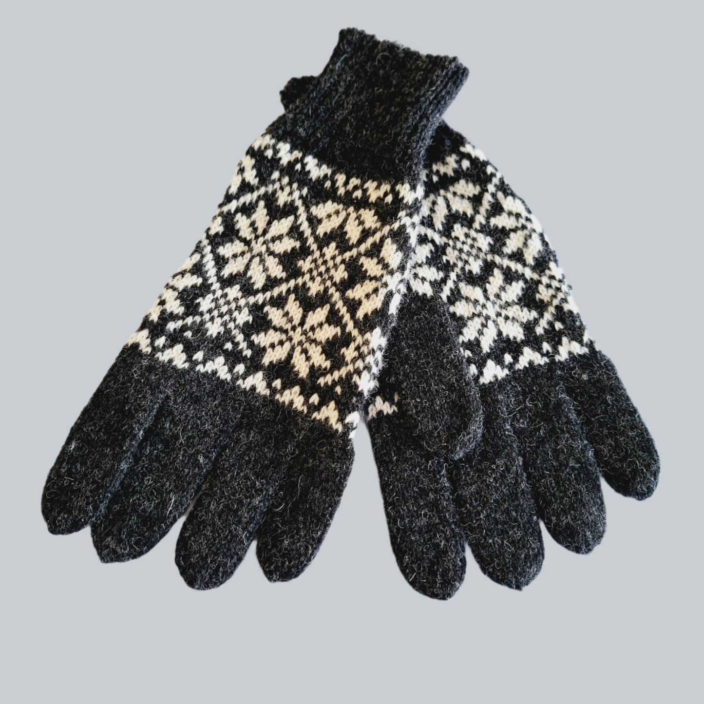 Gestrickte Wollhandschuhe in Hellgrau mit schwarzen Sternen.